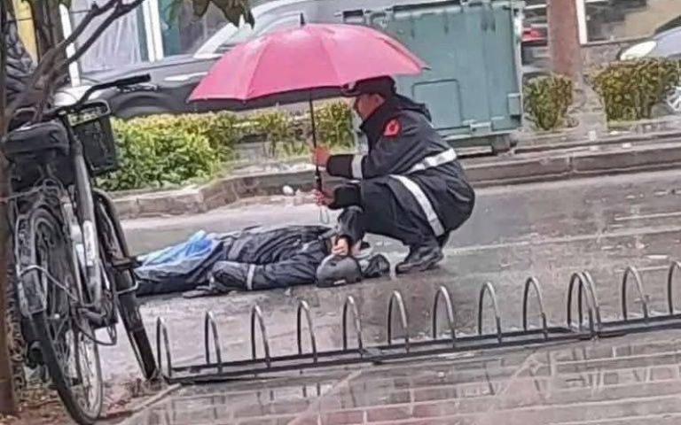 في لقطة إنسانية.. رجل أمن يستعمل مظلته لحماية مواطن مصاب في حادث سير من الأمطار - صورة